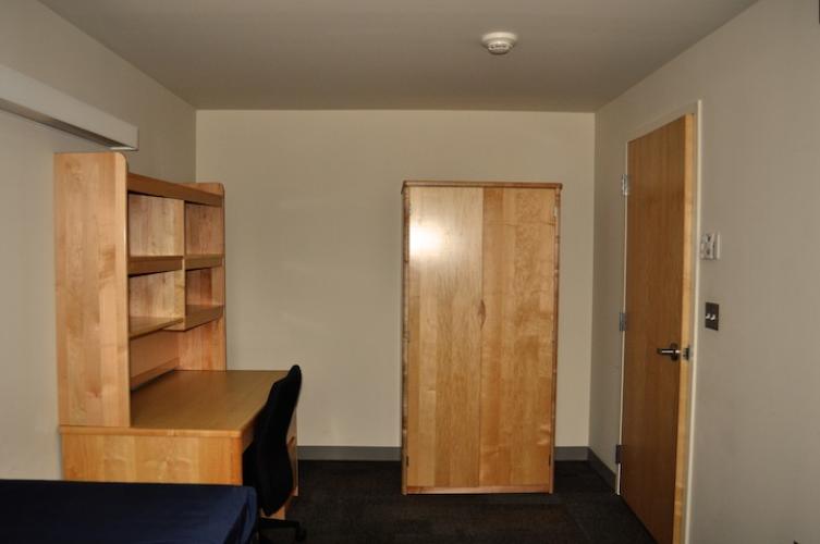 Bedroom showing desk with shelves above the desk for storage.