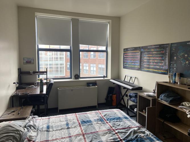 Study desk with chair, windows, piano, and posters.