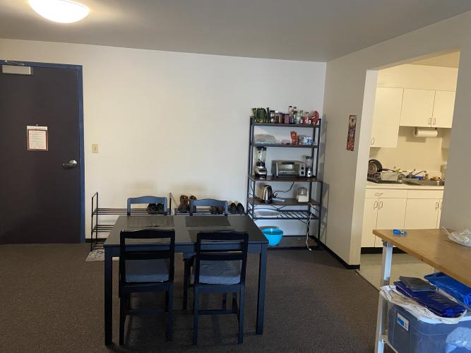 Table and chairs for dinning, and bookcase with kitchen appliances.