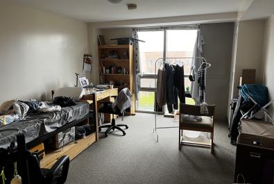 wall-to-wall carpet, floor-to-ceiling windows, facing southeast, twin-size bed with mattress, desk, chairs and rack